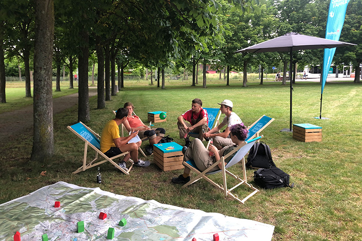 Mitarbeiter des Amtes für Kinder, Jugend und Familie im Gespräch mit vier Jugendlichen im Escholzpark. 