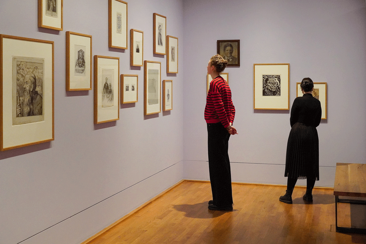 Zwei Personen stehen vor Bildern und schauen sie an