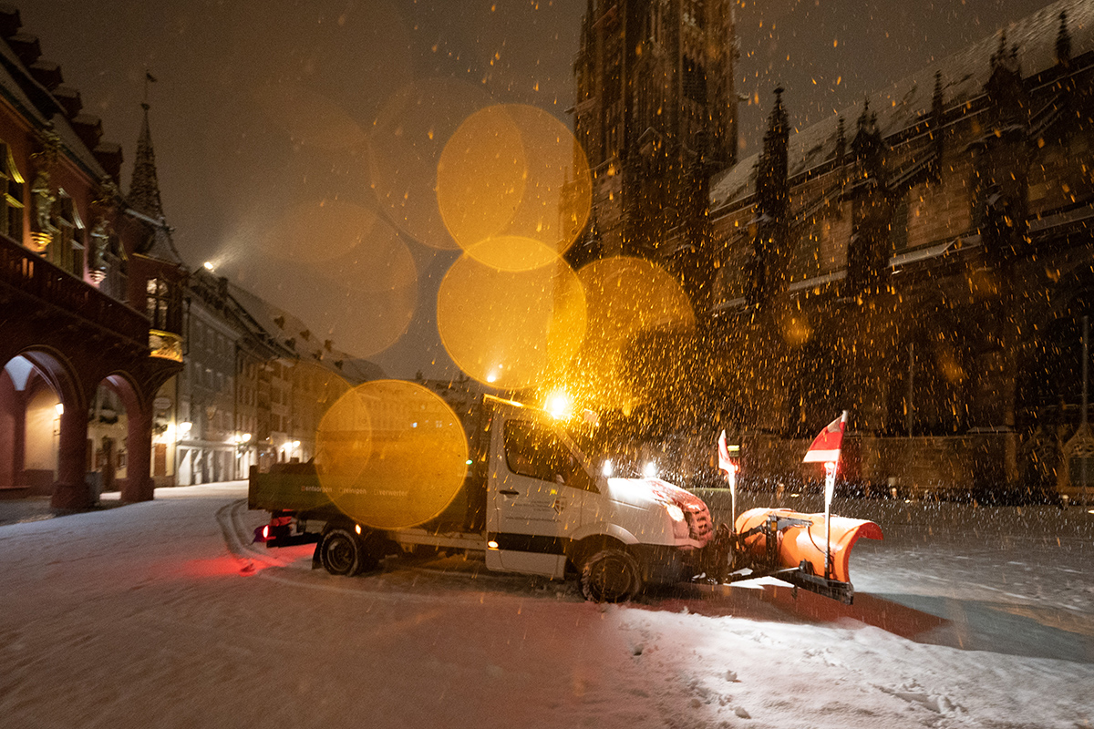 Ein Fahrzeug räumt Schnee auf dem Münsterplatz bei Dunkelheit