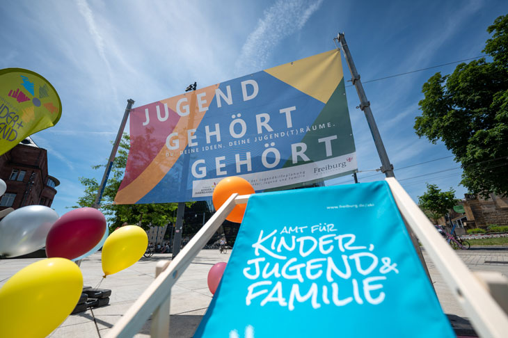 Logo der Aktion "Jugend gehört gehört" mit Luftballons und einem beschrifteten Stuhl des "Amtes für Kinder, Jugend und Familie"