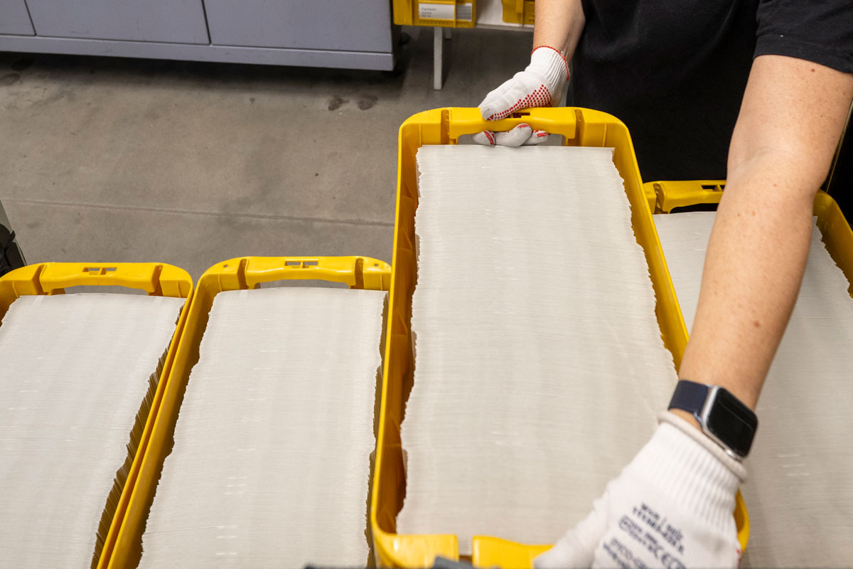 Eine Person hält einen Kasten mit sehr vielen Briefumschlägen