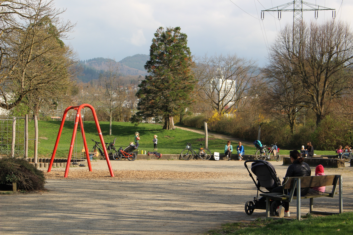 Belebter Spielplatz mit rotem Schaukelgerüst