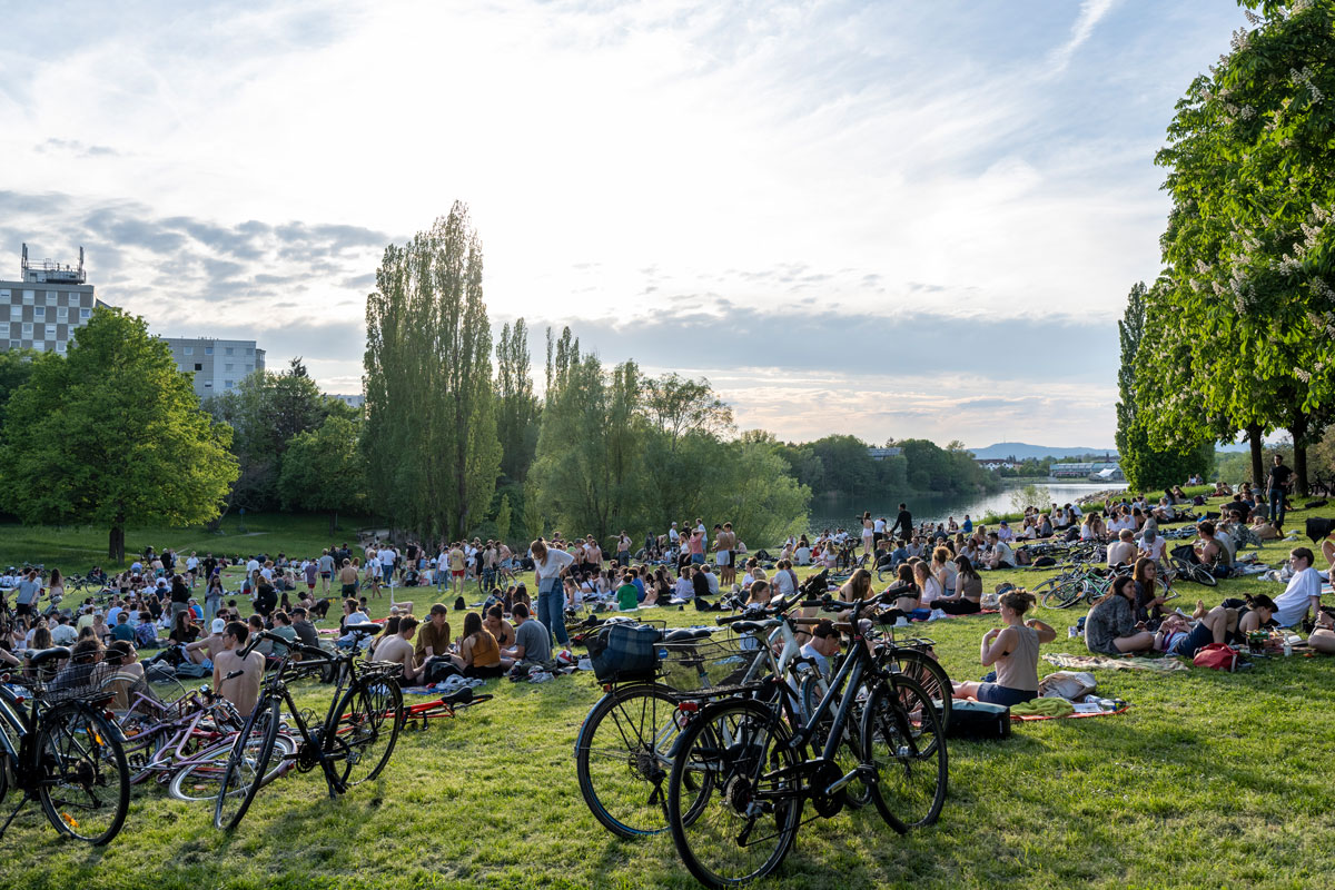 Viele Menschen auf einer Wiese am See