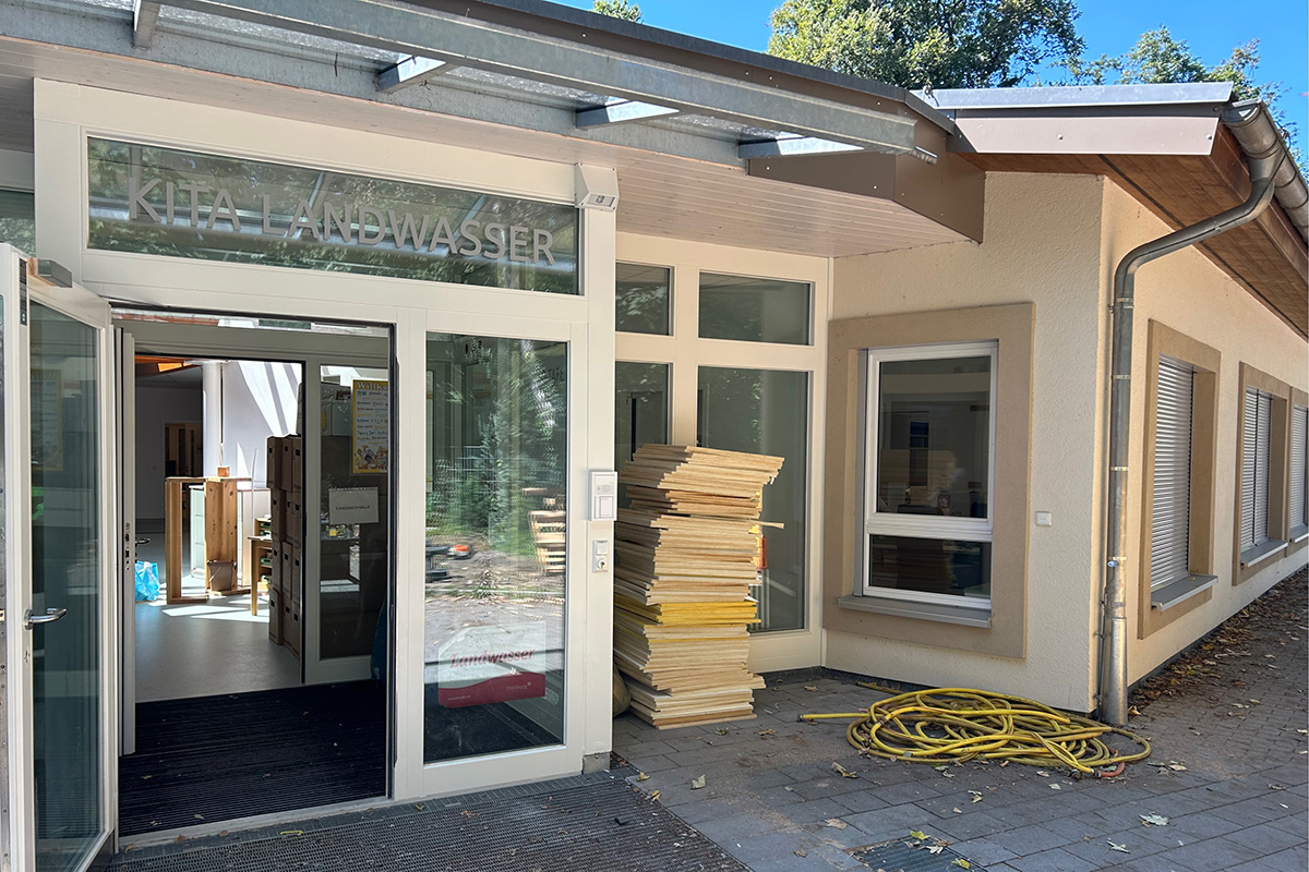 Eingang eines Gebäudes, die verglaste Eingangstür ist offen.