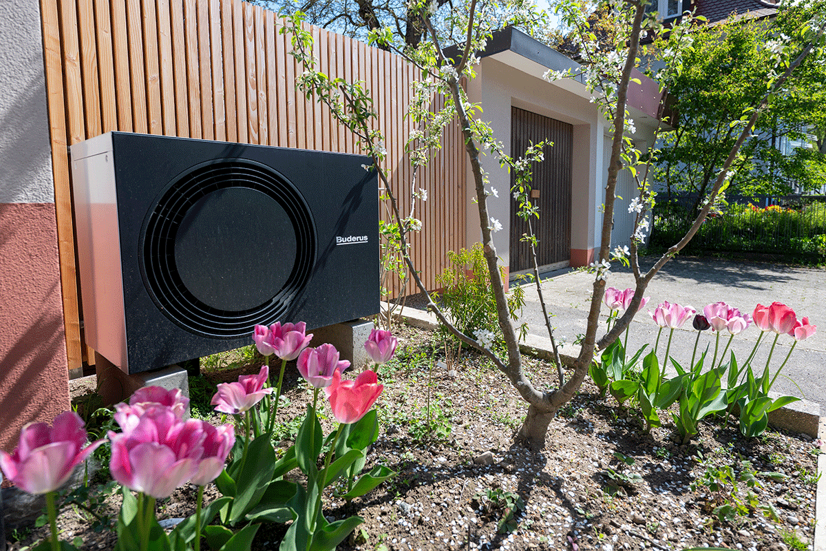 Installierte Wärmepumpe in einem Vorgarten mit Tulpen Installierte Wärmepumpe