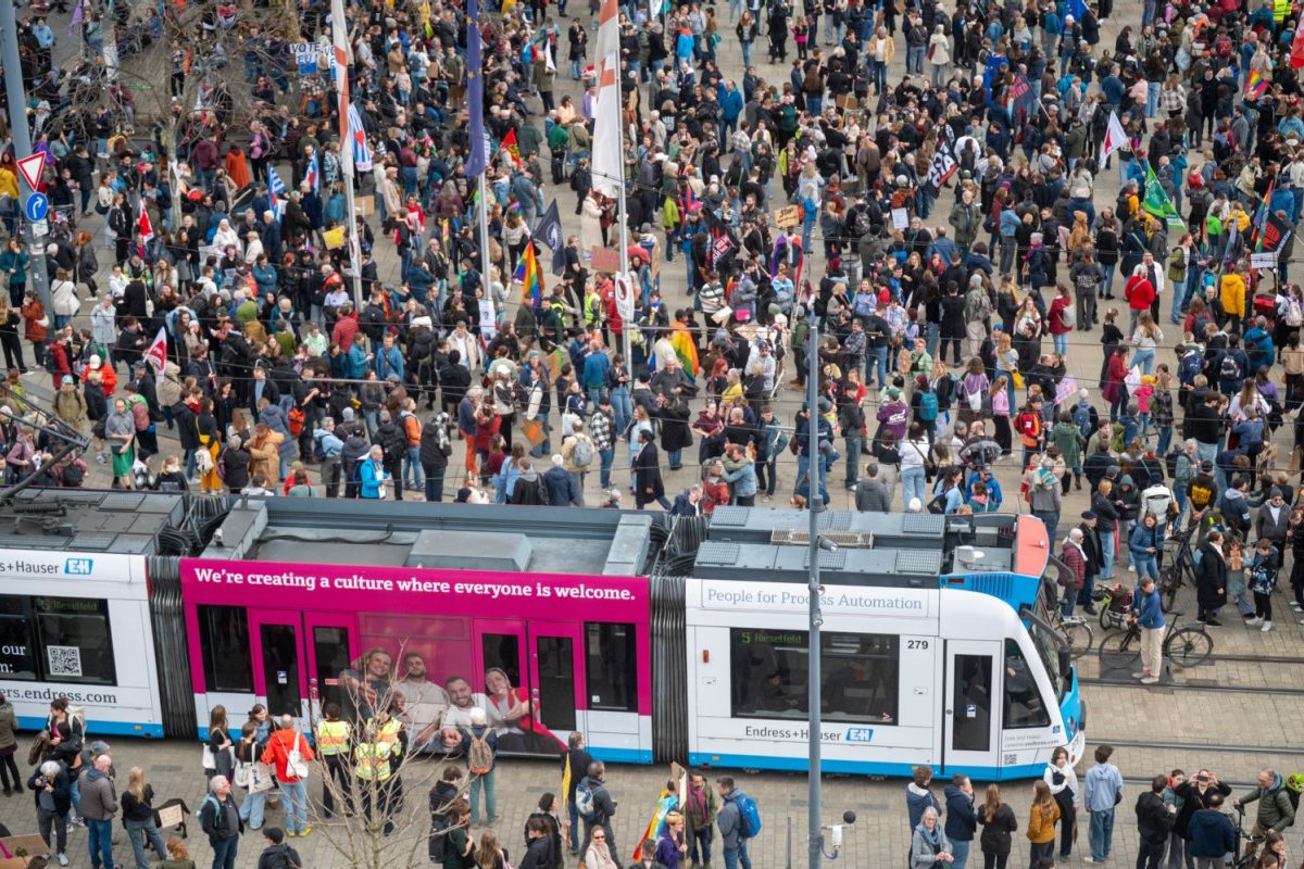 Große Menschenansammlung in der Innenstadt, dazwischen fährt eine Straßenbahn.