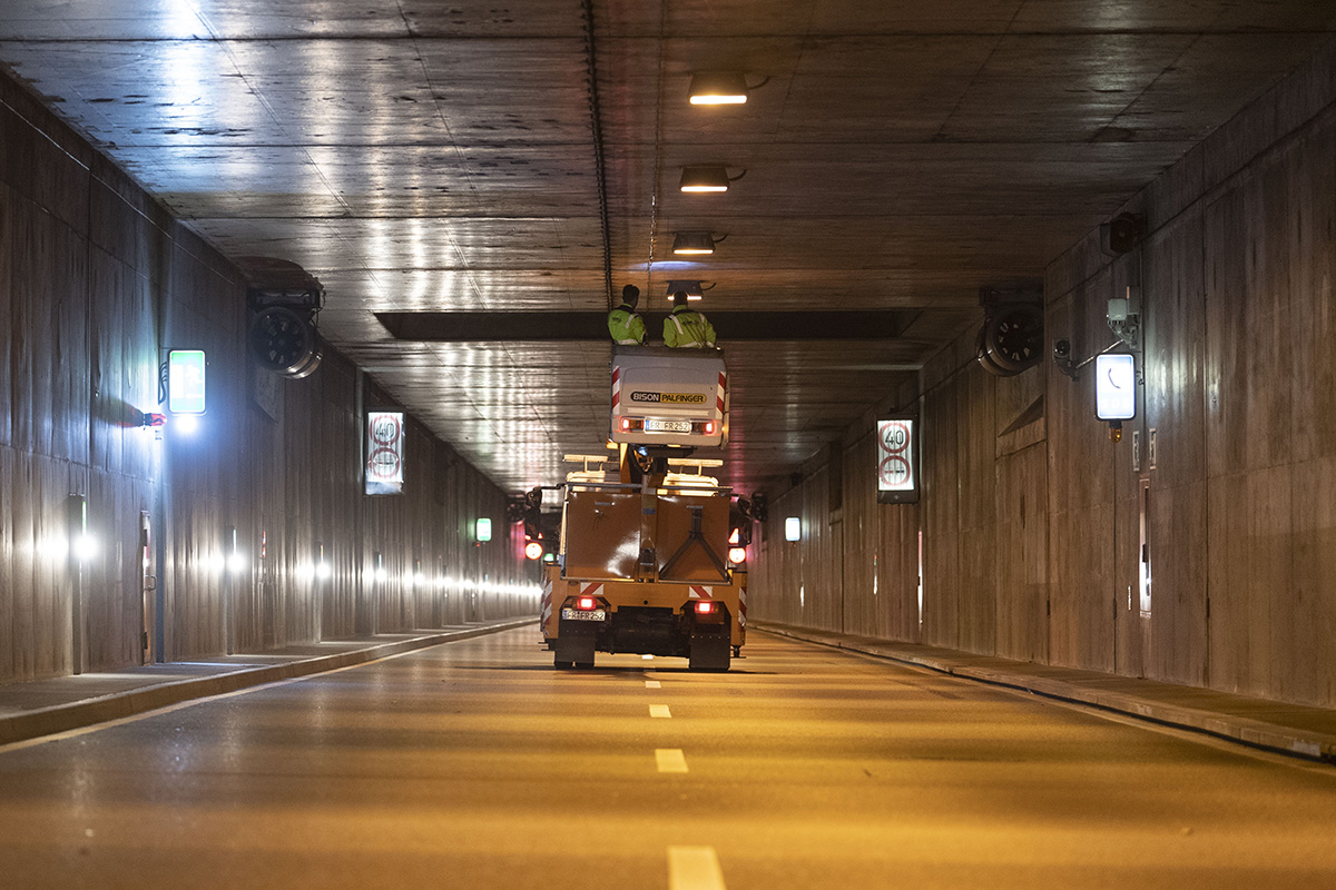 Leerer Tunnel, mittig ein Baustellenfahrzeug mit zwei Personen