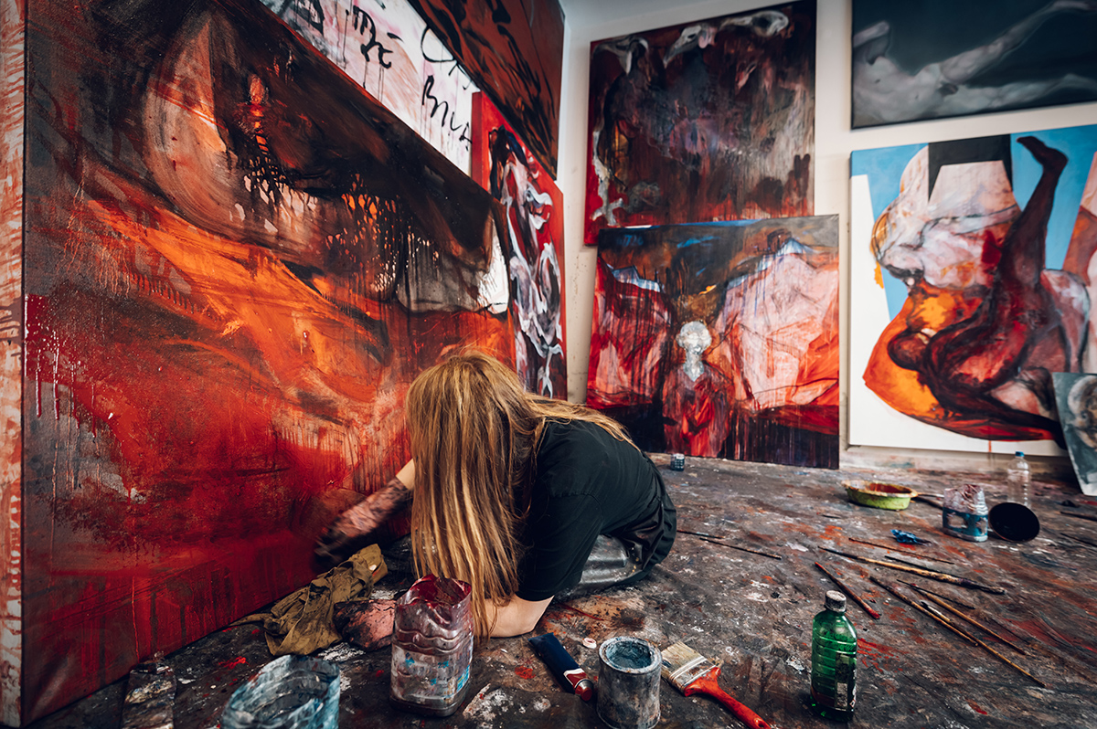 Frau malt auf großen Leinwänden mit Farbe