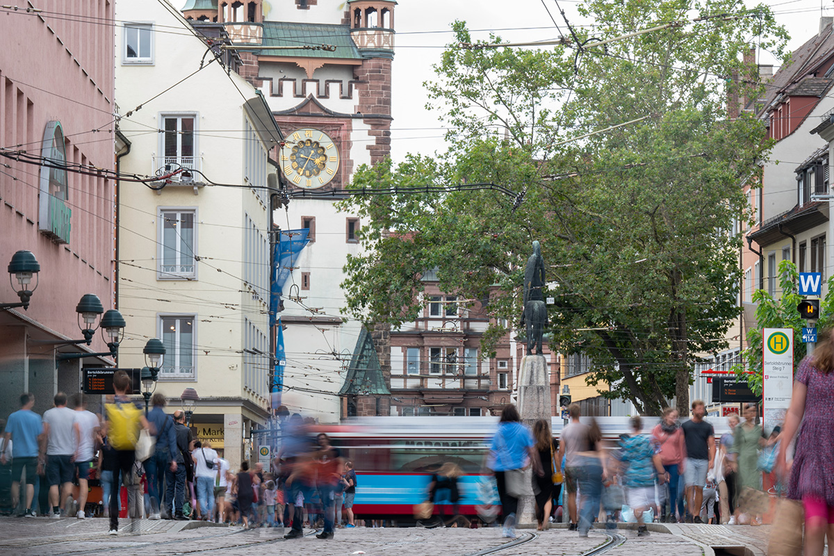 Passantinnen und Passanetn in der Freiburger Innenstadt, im Hintergrund das Martinstor.