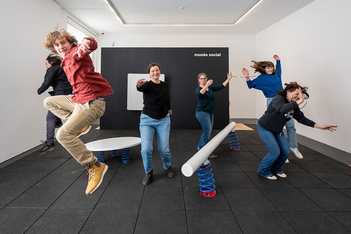 Hüpfende und lachende Personen, die eine spielplatzähnliche Kunstinstallation erkunden