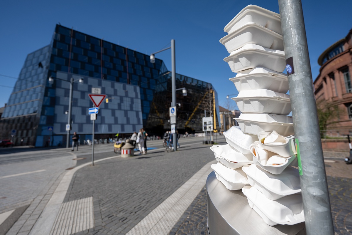 Auf einem Mülleimer stapeln sich viele Styropor-Mehrwegbehältnisse.