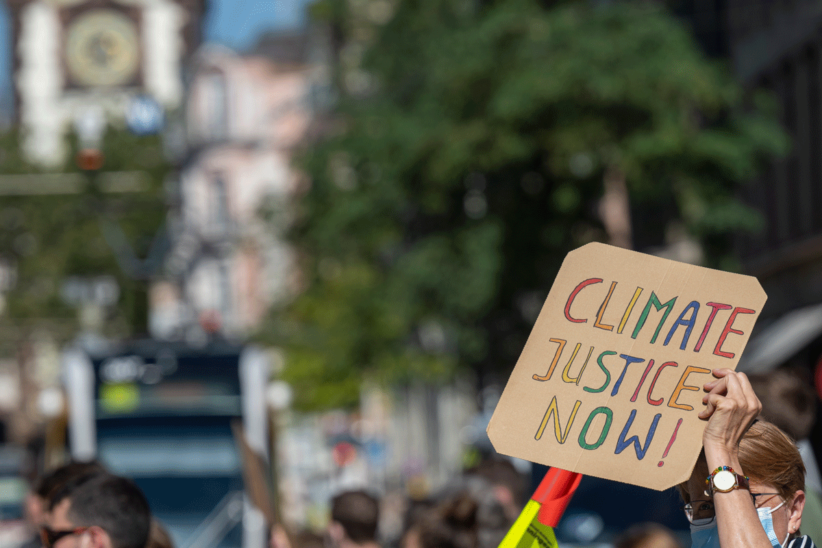 Pappschild: Climate Justice Now, im Hintergrund: Martinstor