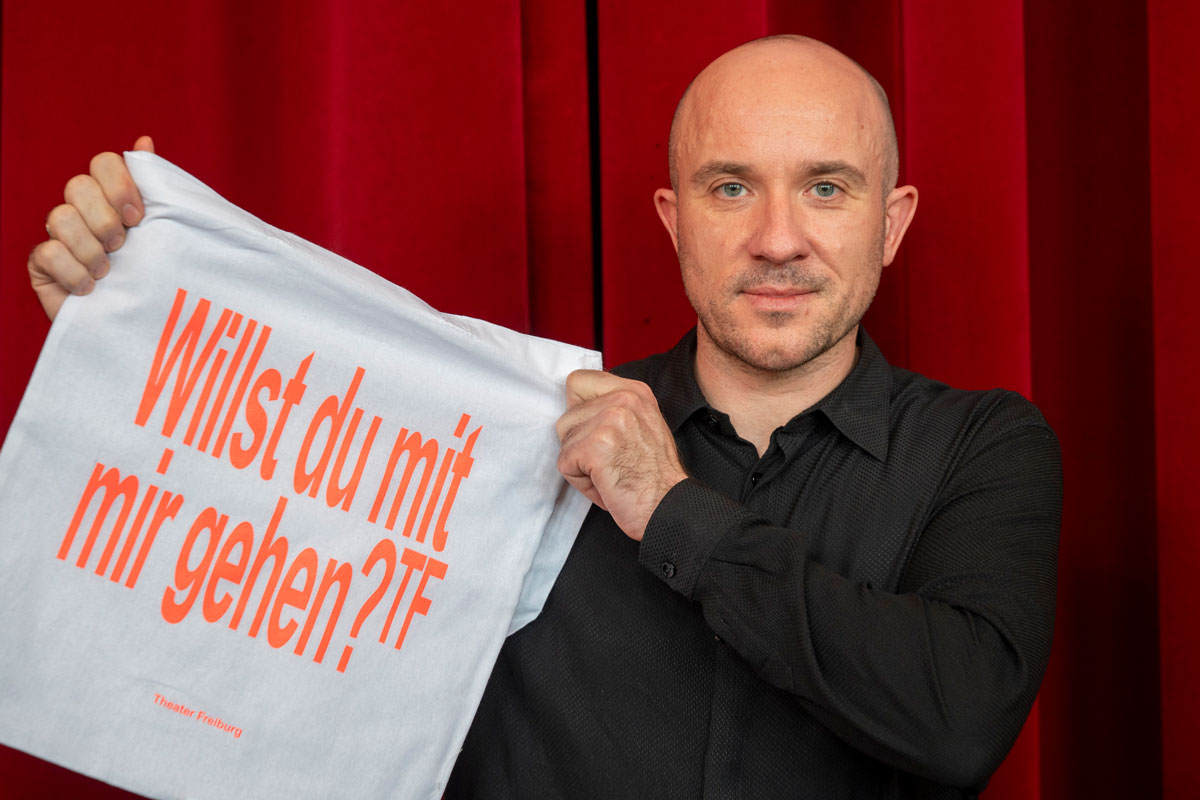 Mann hält Tasche ins Bild mit der Aufschrift 