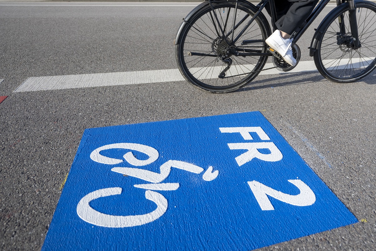 Ein blaues Kästchen ist auf die Straße gemalt, mit einem weißen Fahrradsymbol und der Aufschrift: FR 2; gerade fährt ein Fahrrad vorbei.