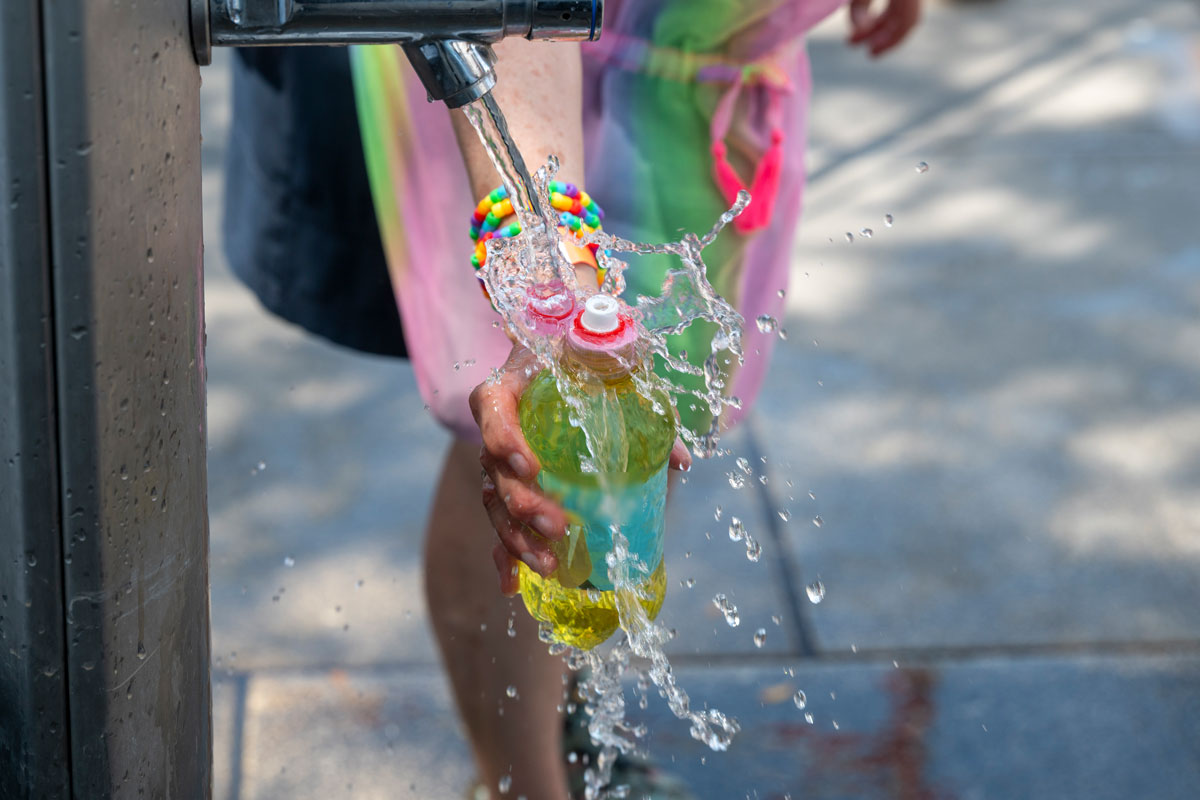 Eine Person füllt eine Trinkflasche an einem Trinkbrunnen auf
