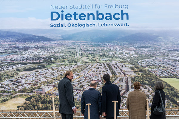 Menschengruppe von hinten vor Plakat zu Dietenbach
