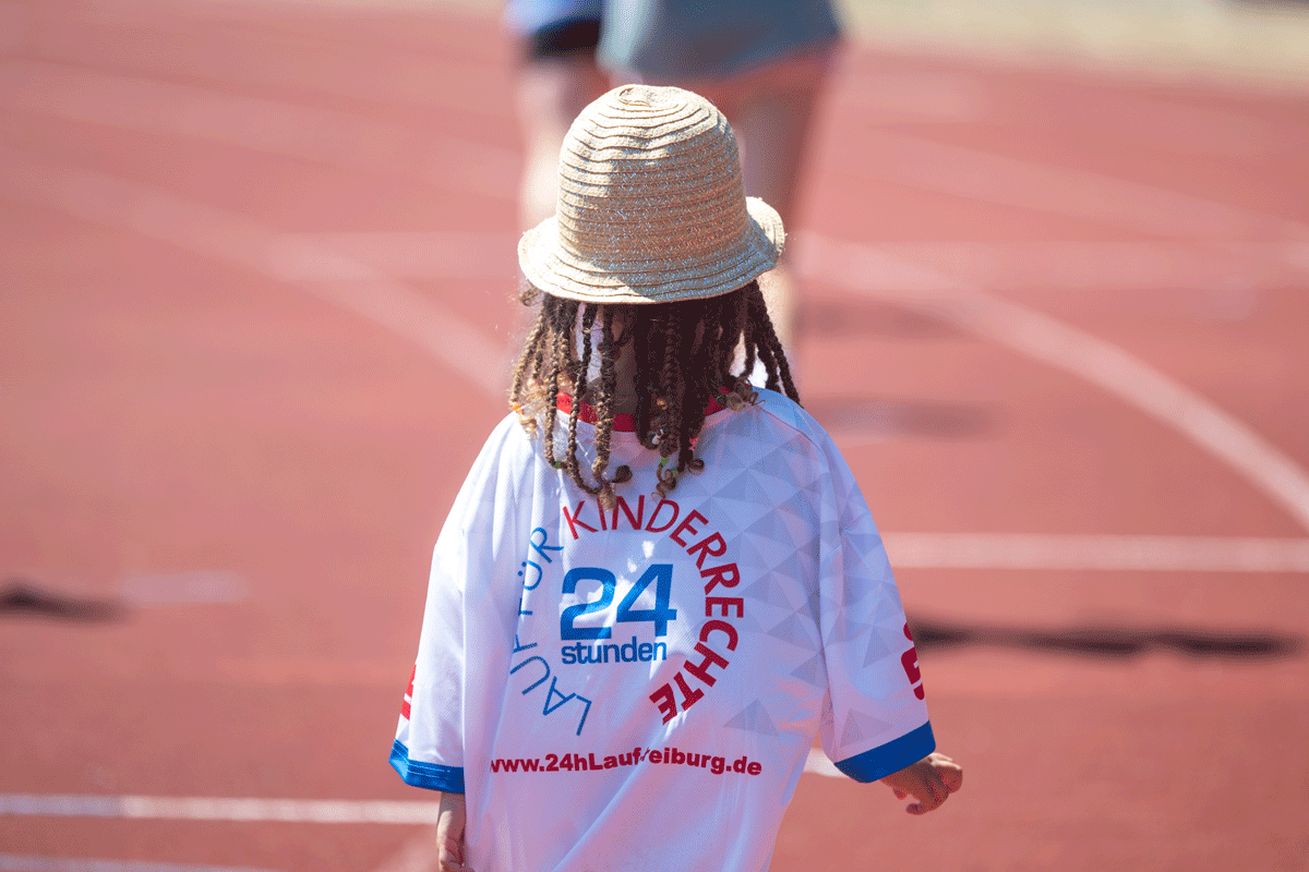 Kleines Kind rennt auf einer Laufbahn