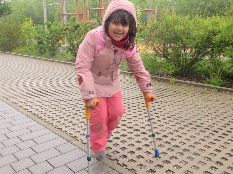 Ein Mädchen läuft an zwei Gehhilfen.