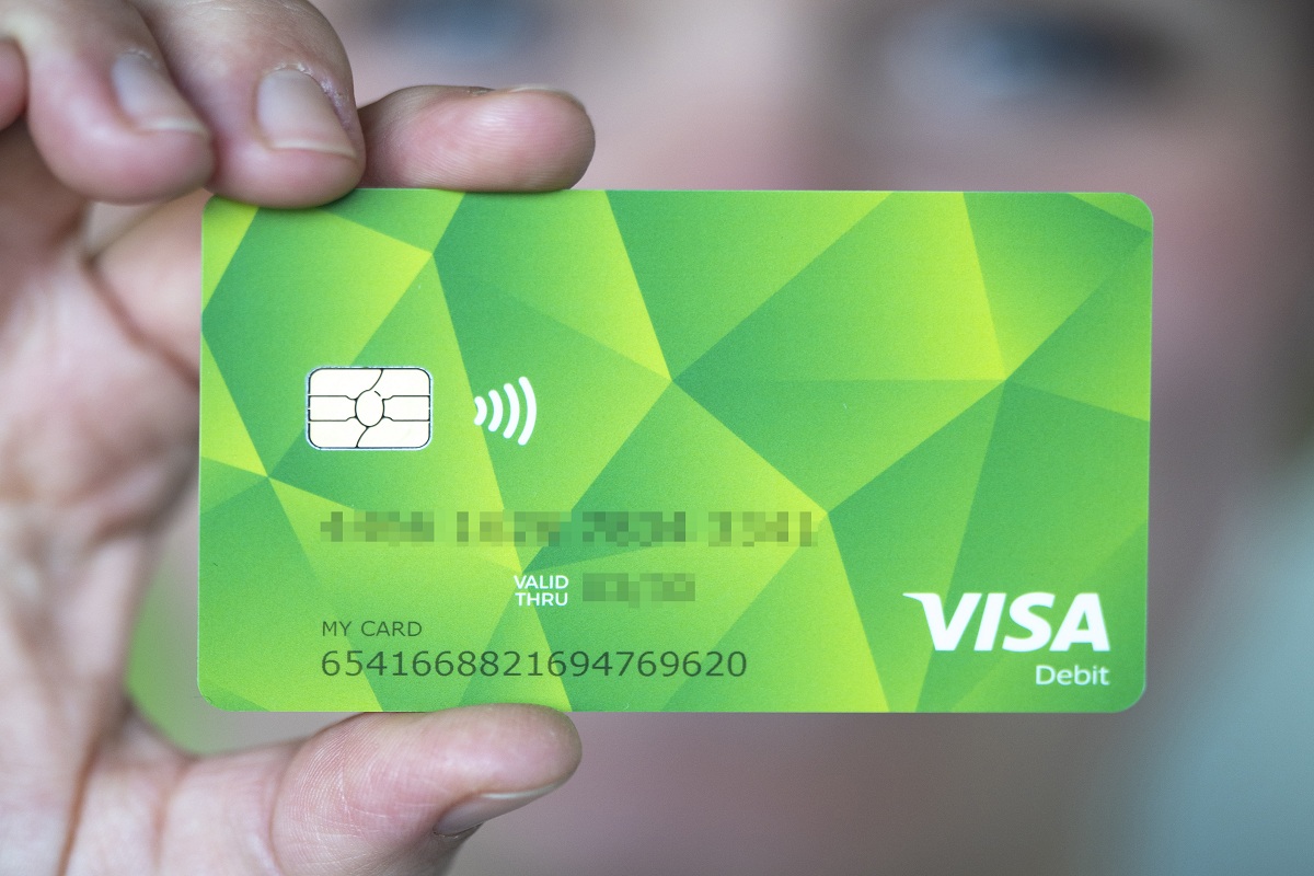 Eine Person hält die grüne Bezahlkarte in die Kamera.