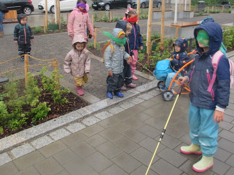 Mit verbundenen Augen und Langstock laufen Kinder durch das Quartier.