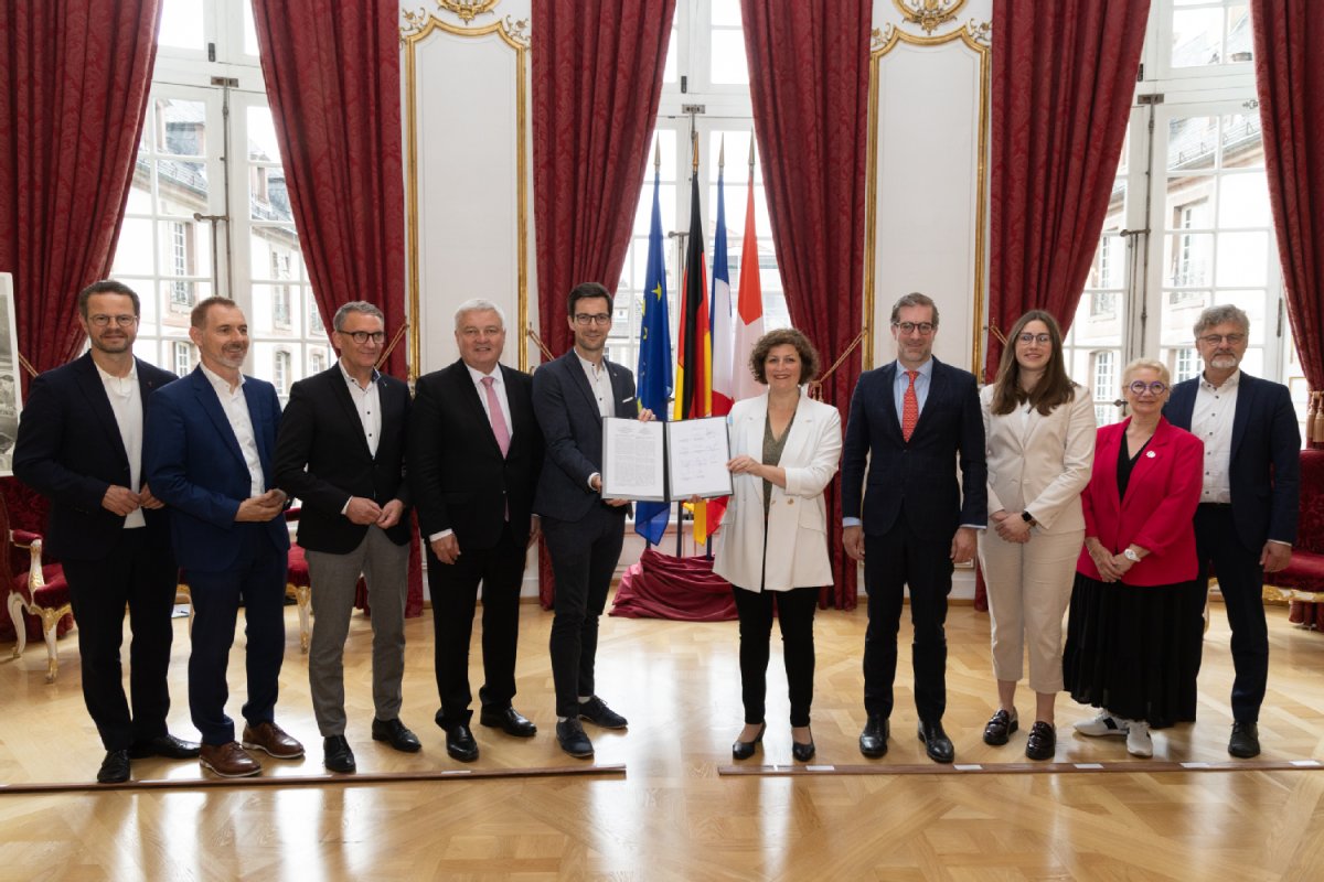 Bürgermeister*innen des Städtenetzes in einer Reihe, in der Mitte wird ein Buch hochgehalten.