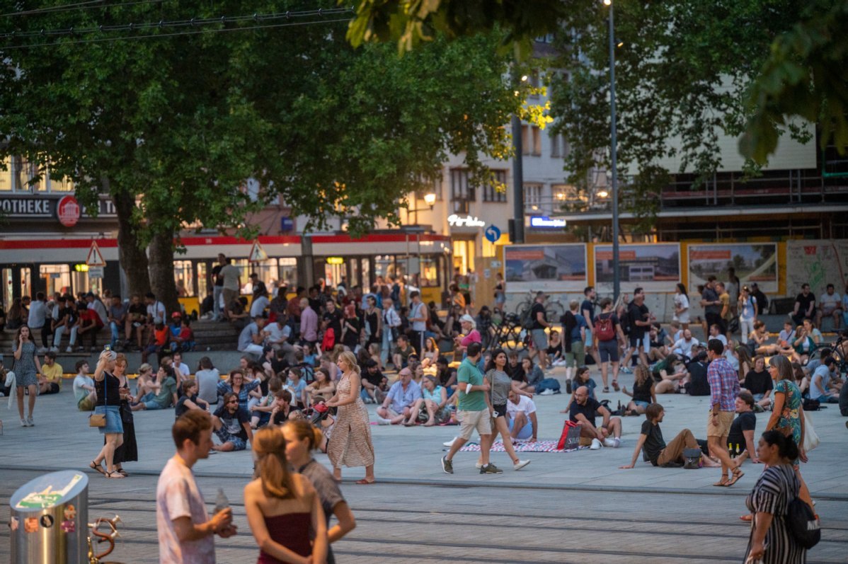 Der Platz der alten Synagoge in der Dämmerung, viele Menschen sind hier versammelt, im Hintergrund eine Straßenbahn
