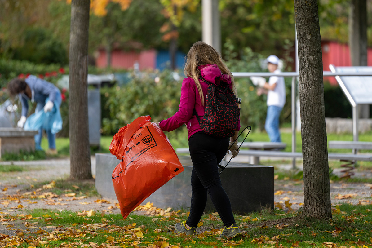 Frau mit Müllsack und Müllzange