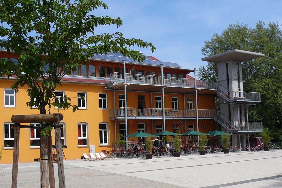 Gepflasterter Platz und Gebäude und Freisitzflächen mit Sonnenschirmen 