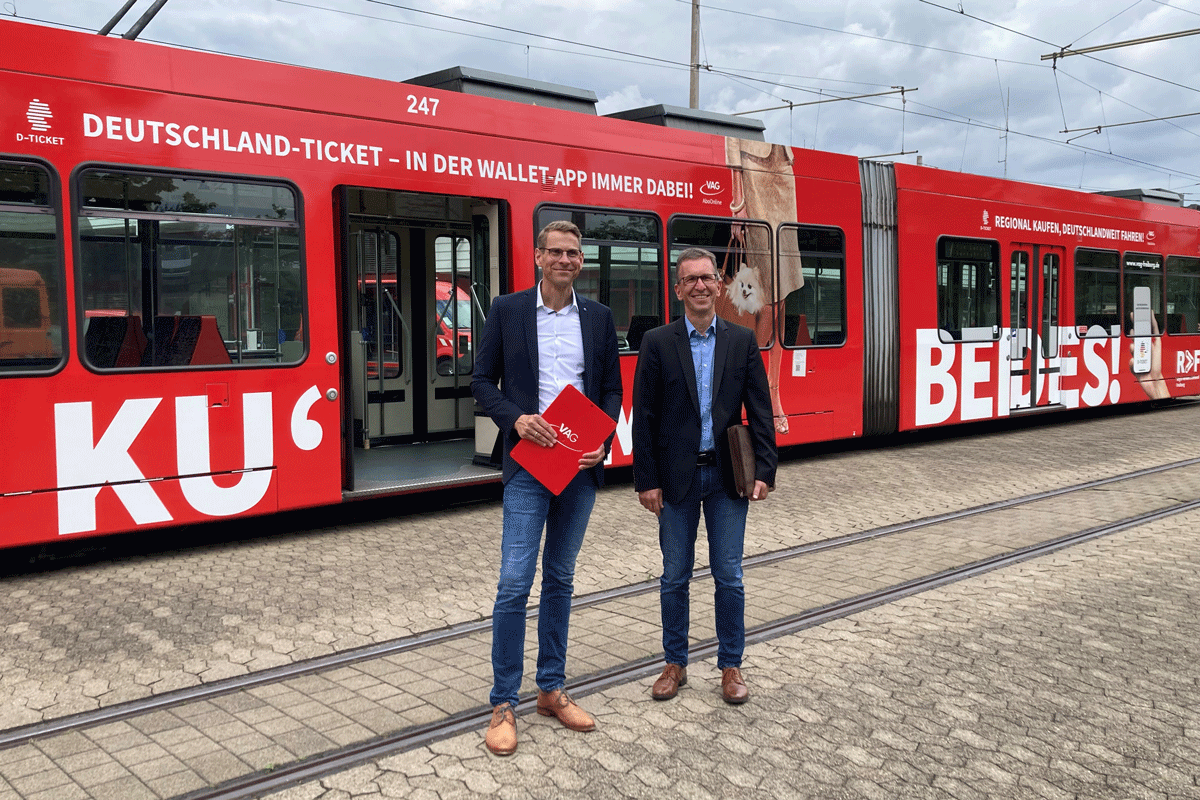 Zwei Männer stehen vor einer roten Straßenbahn