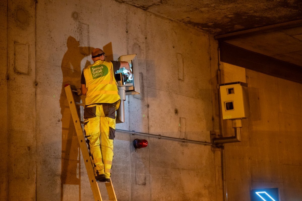 Ein Arbeiter auf einer Leiter, er tüftelt am Stromkasten an der Innenwand vom Tunnel