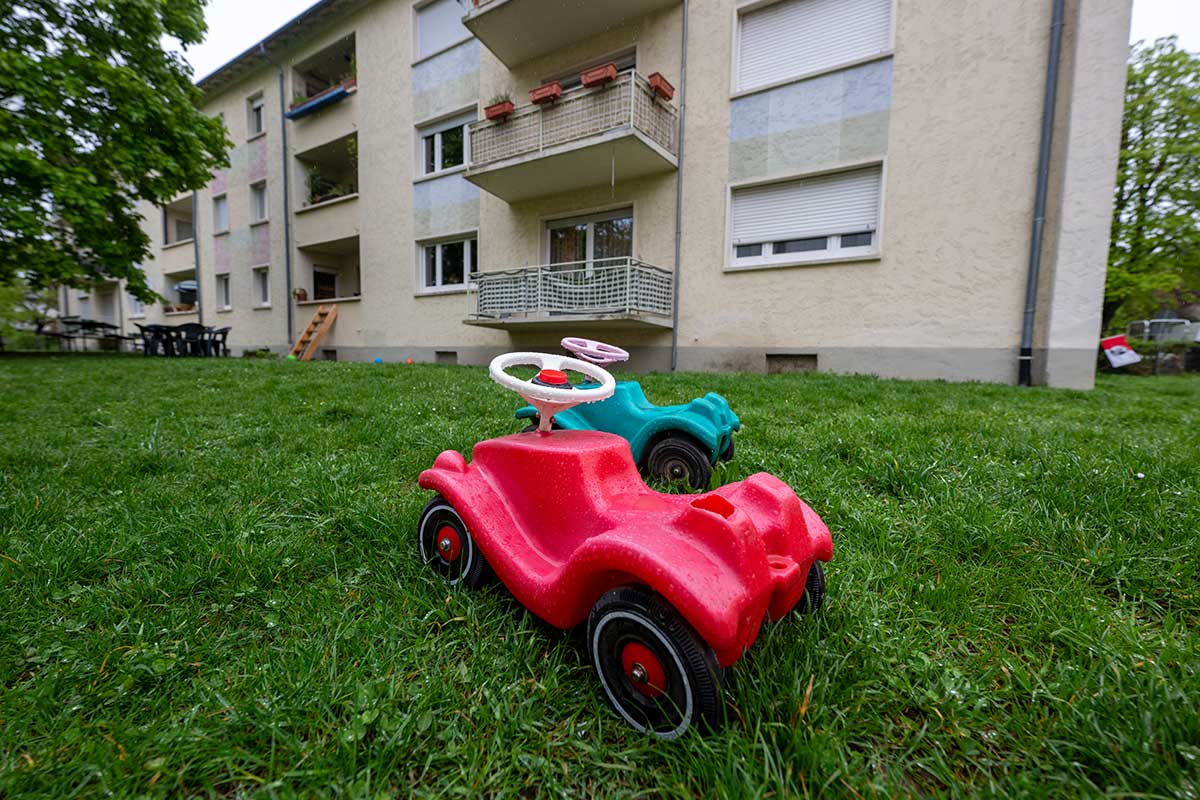 Bobycar im Rasen vor Mehrfamilienhaus