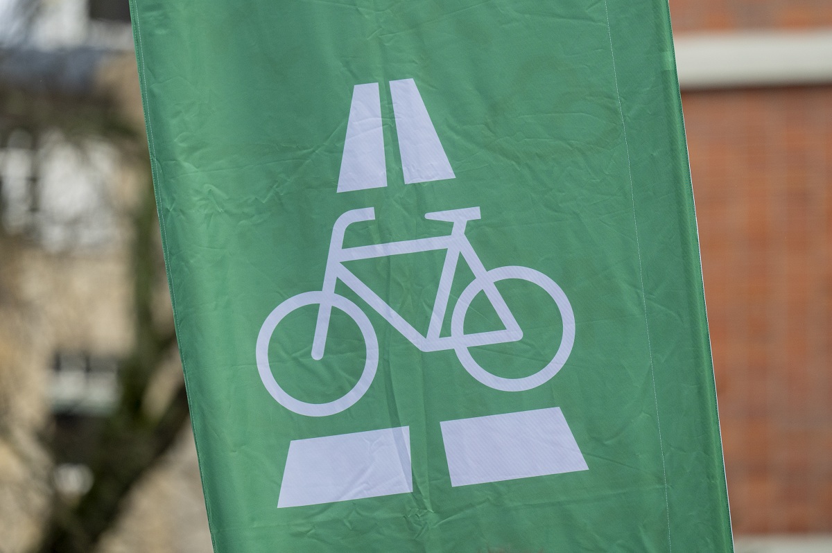 Eine grüne Fahne mit dem Logo des Radschnellwegs: Ein Autobahnzeichen mit einem Fahrrad.