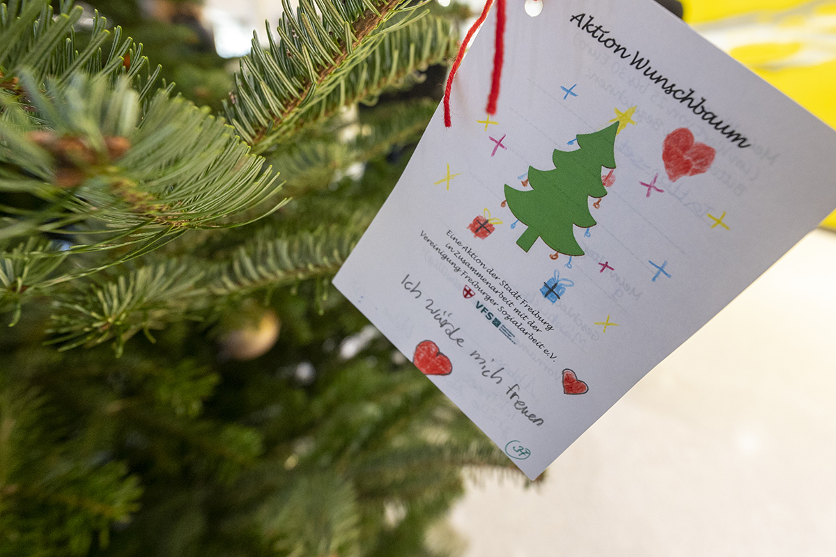 Weihnachtsbaum mit einer Karte, auf der ein Wunsch eines Kindes steht