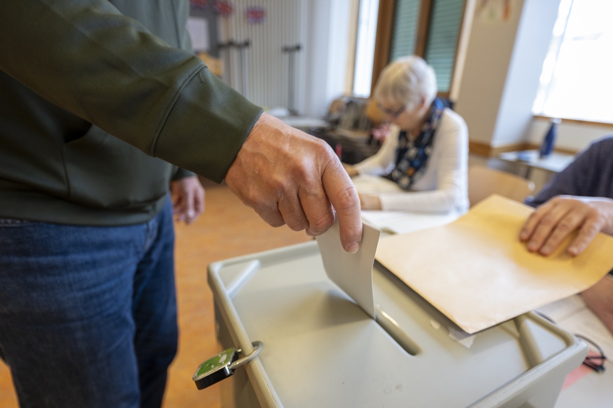 Jemand wirft seinen Stimmzettel in die Wahlurne.