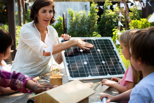 Foto: Rawpixel/istock.com Eine Frau erklärt einer Gruppe Kinder ein Solarpaneel