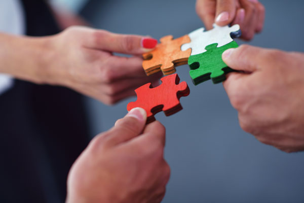 Menschen halten Puzzleteile aneinander