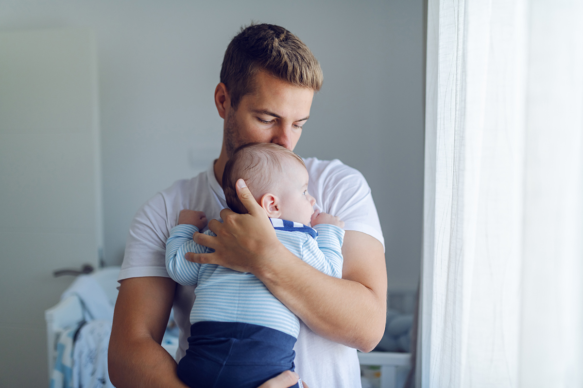 Junger Mann mit Baby auf dem Arm