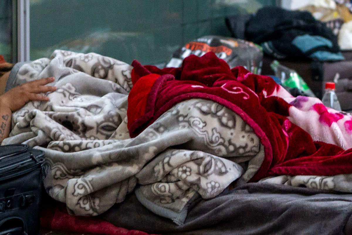 Obdachlose Person liegt auf dem Boden mit mehreren Decken