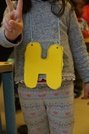 Ein Kind trägt den Buchstaben "H" an einer Kette.