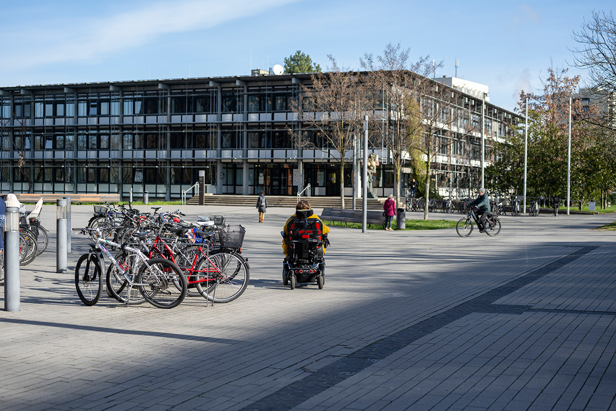 Eine Person im Rollstuhl fährt auf das Gebäude zu, in dem sich die Ansprechstelle befindet