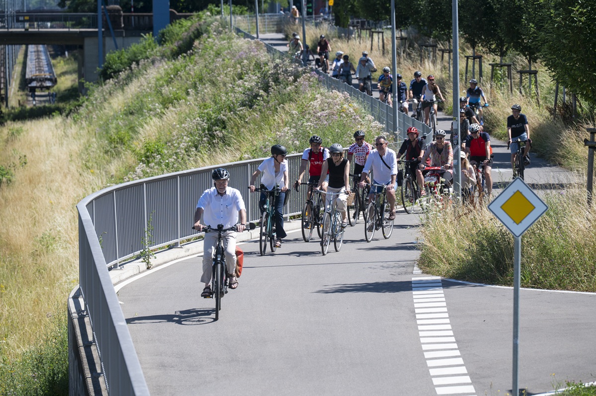 Banner fürs Stadtradeln über der Wiwili-Brücke, davor Radler*innen von hinten 