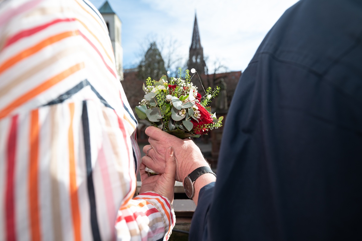 Ein älteres Ehepaar hält einen Blumenstrauß in den Händen.