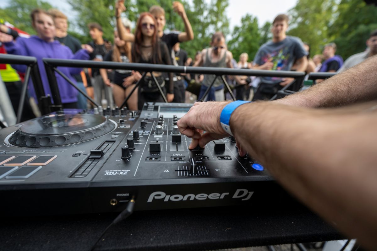Ein DJ-Pult mit tanzenden Menschen im Hintergrund