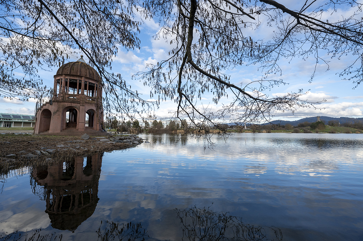 Links im Bild ein kleines Tempelchen, rechts die Parkanlage mit See