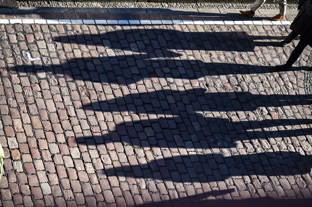 Schatten mehrerer Menschen auf Kopfsteinpflaster