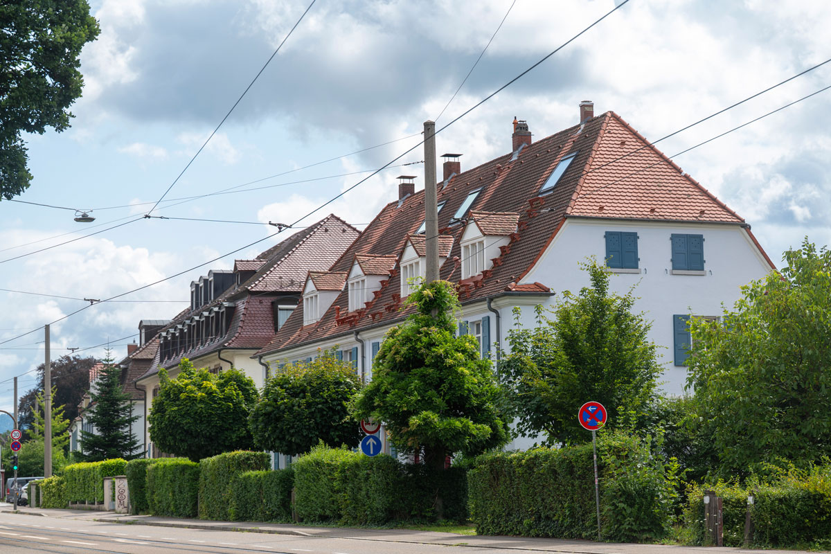 Straße mit Wohnhäusern und grünen Vorgärten