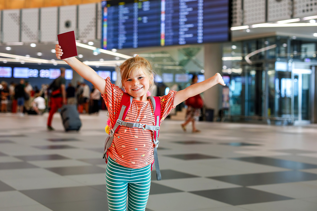 Fröhliches Mädchen mit Reisepass am Flughafen