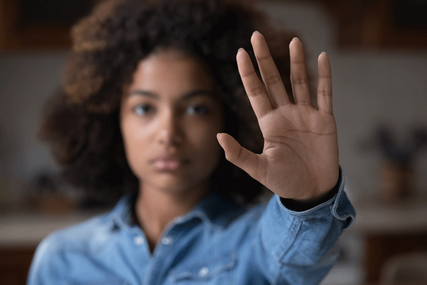Foto: fizkes/istockphoto.com Frau hält Hand vor sich mit Schwirftzug "Stop"