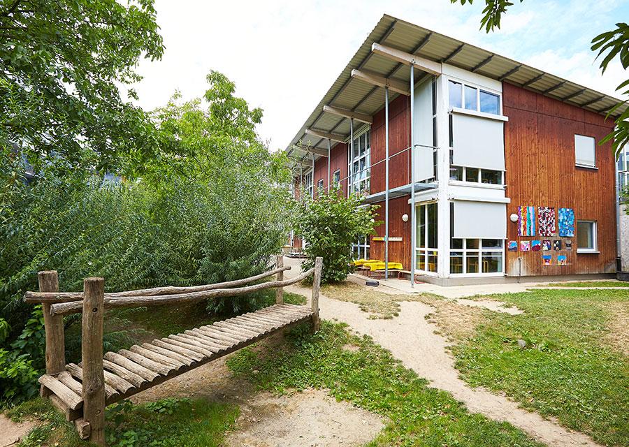 Außenansicht der Kita Rieselfeld mit Holzsteg im Garten