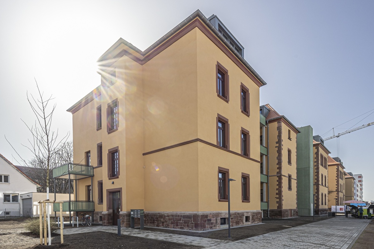 Ein großes gelbes Gebäude an einer Straße mit mehreren Wohnungen und Balkonen.